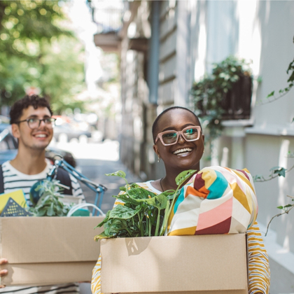 To students chatting while carrying boxes down street to new apartment